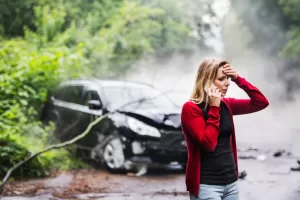 woman with smartphone by the damaged car after a car accident